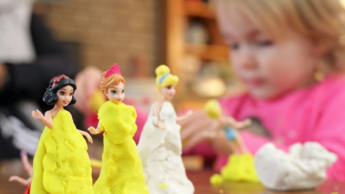 Crianças fazendo roupas de massinha para bonecas